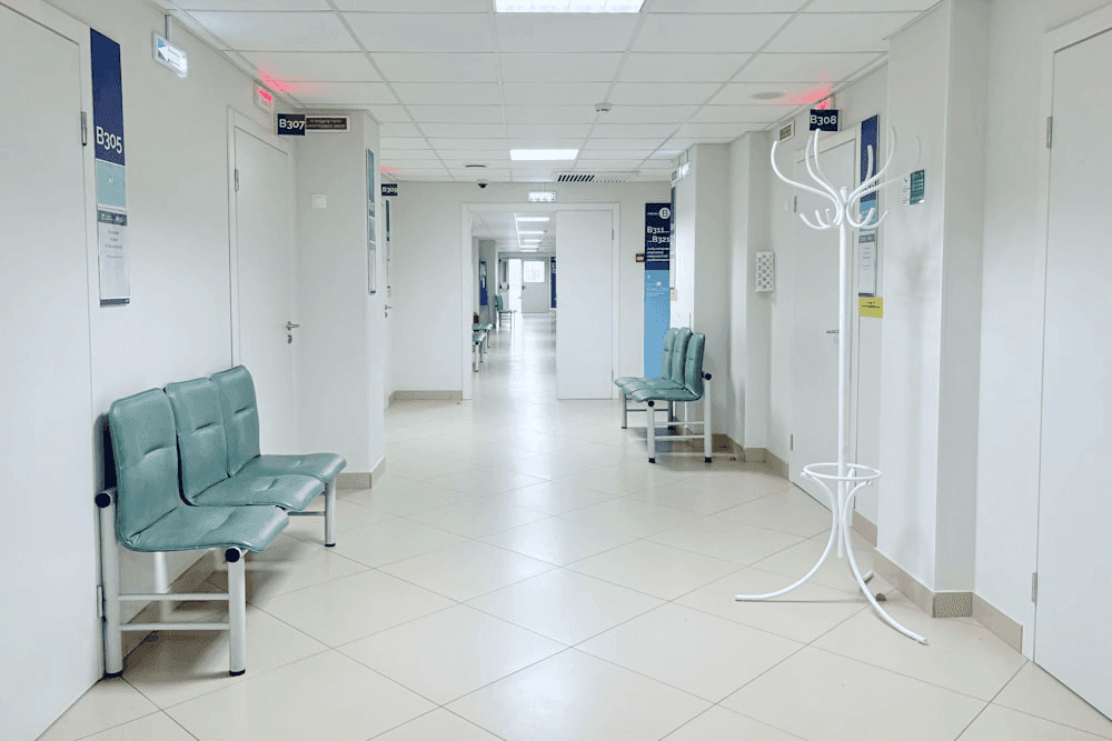 Modern hospital corridor with clinical lighting and empty gurneys, no patients visible