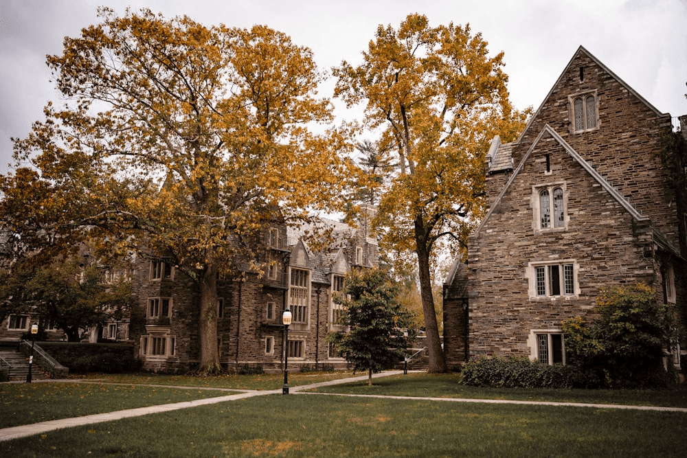 Private school campus with stone buildings, green lawn, and tree-lined walkway