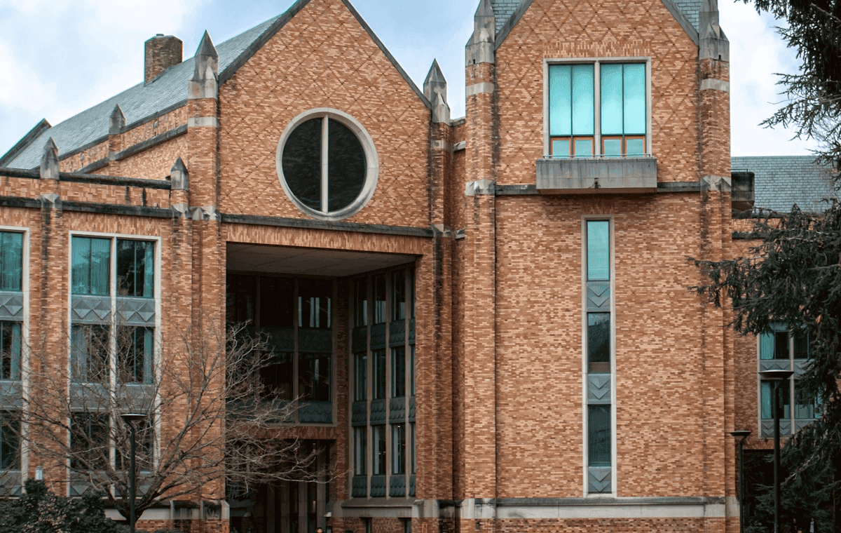 Private school campus building with stone facade and tree-lined walkway at dusk